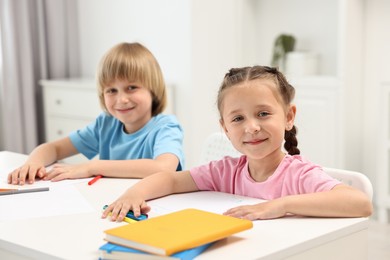 Photo of Cute little children drawing at table indoors