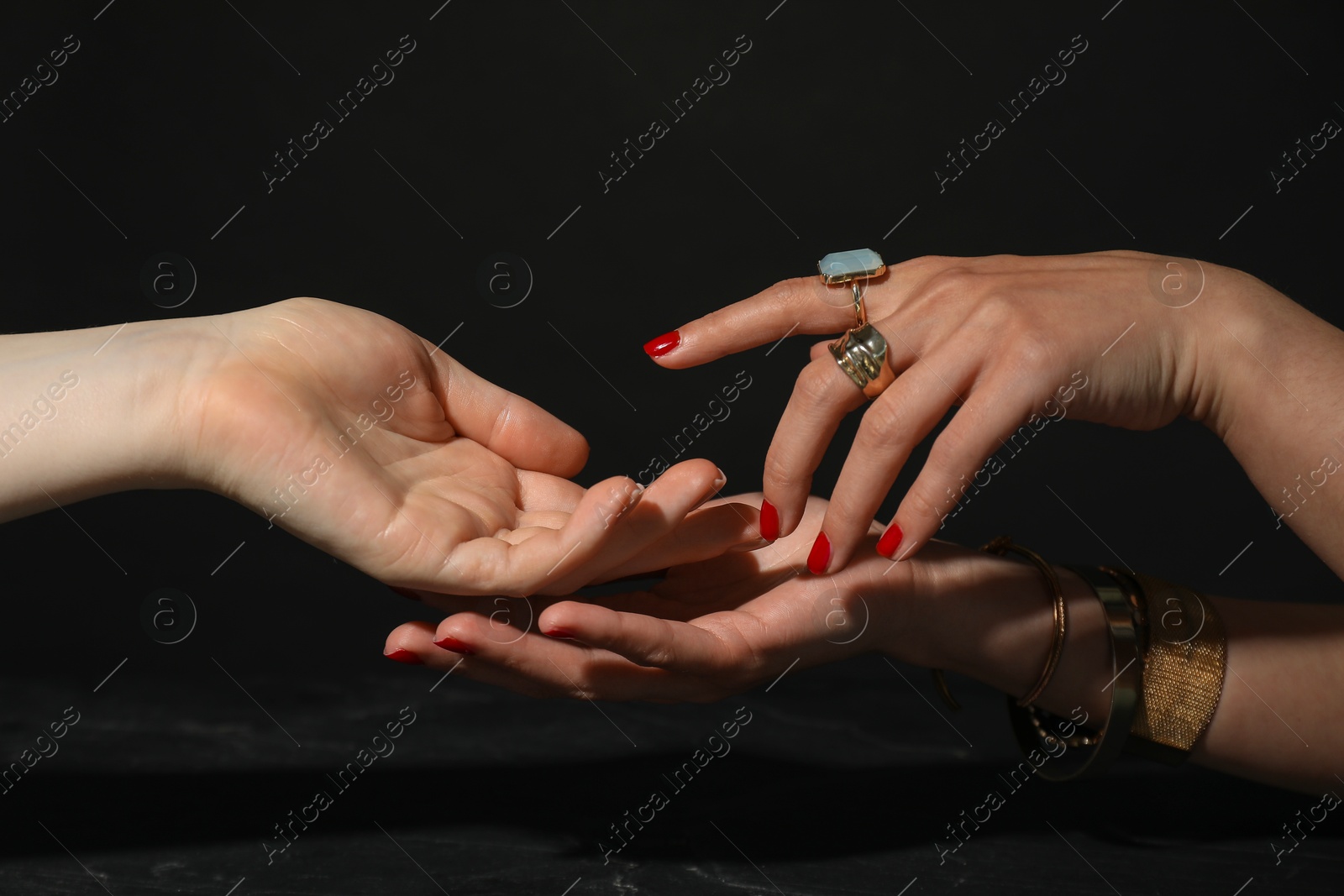 Photo of Fortune teller reading lines on woman's palm at dark grey table, closeup. Chiromancy