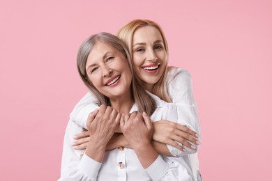 Photo of Family portrait of young woman and her mother on pink background