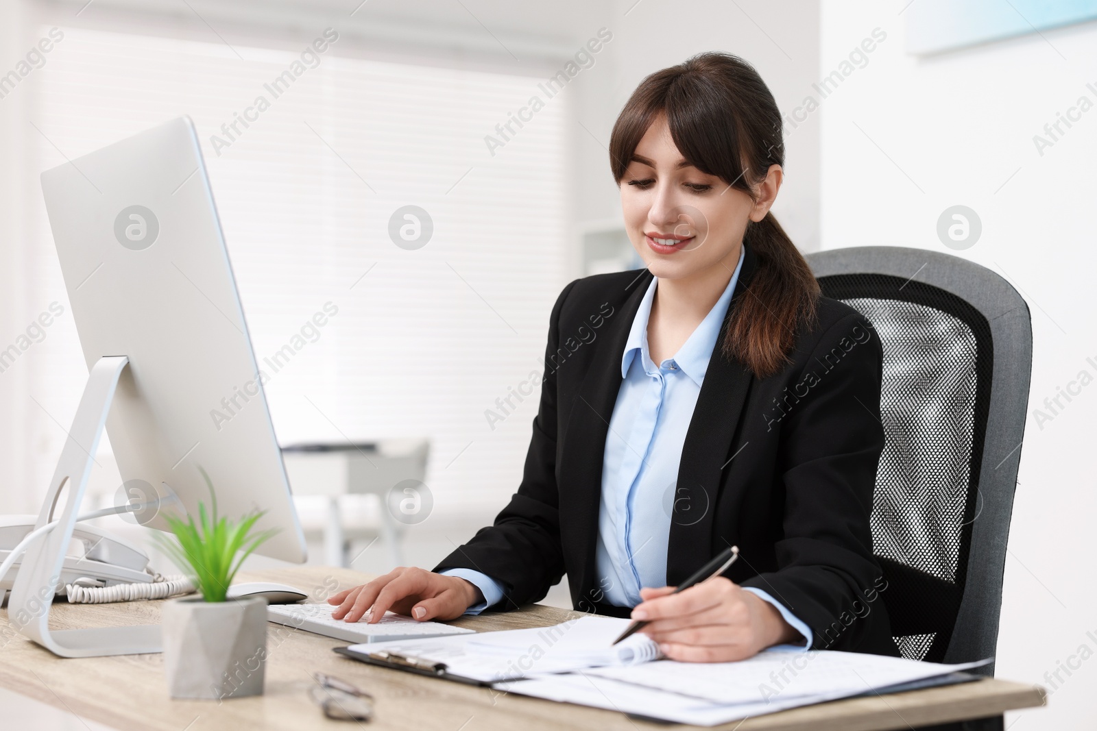 Photo of Smiling secretary working at table in office