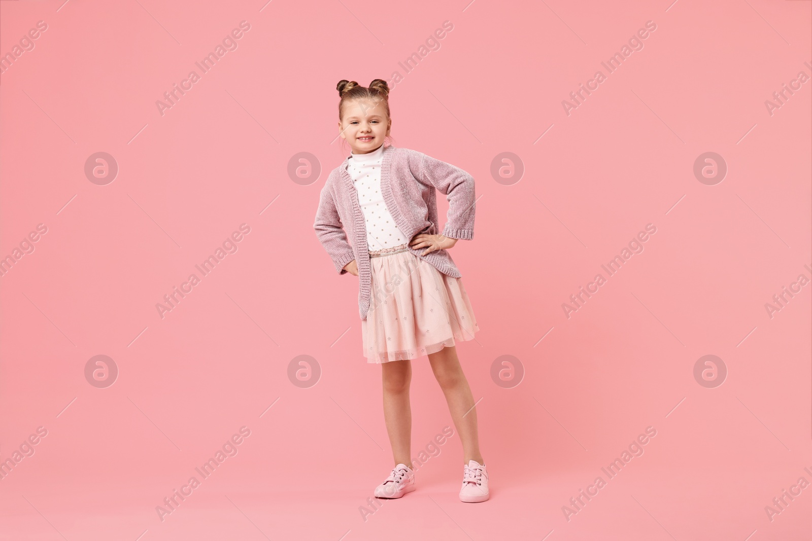 Photo of Cute little girl dancing on pink background