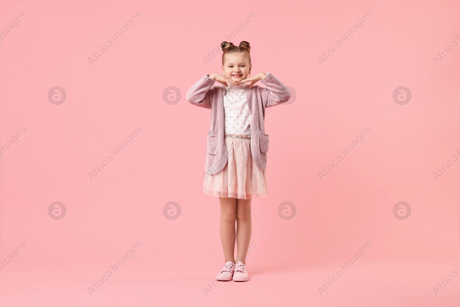 Photo of Cute little girl dancing on pink background