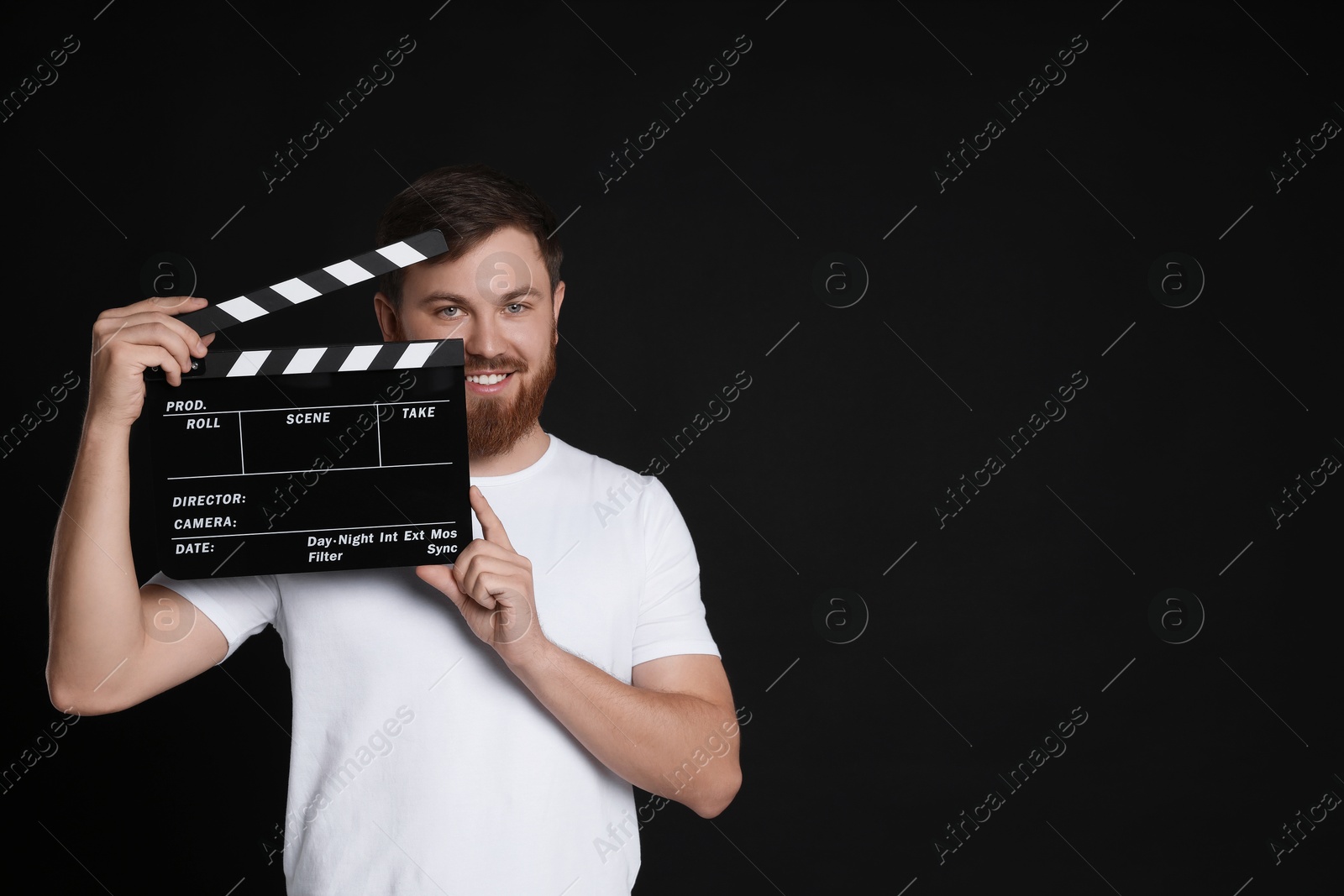 Photo of Making movie. Smiling man with clapperboard on black background. Space for text