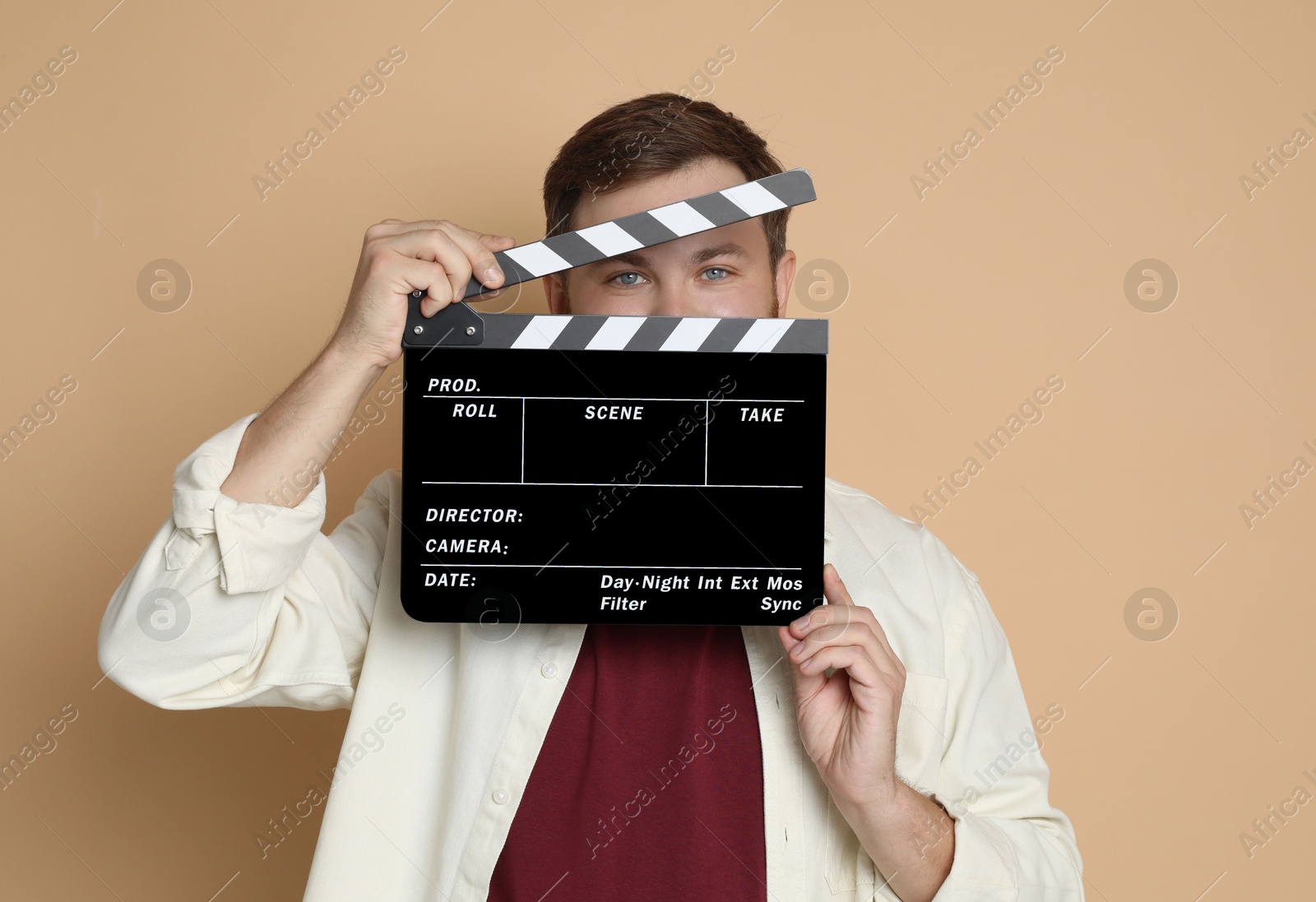 Photo of Making movie. Man with clapperboard on beige background