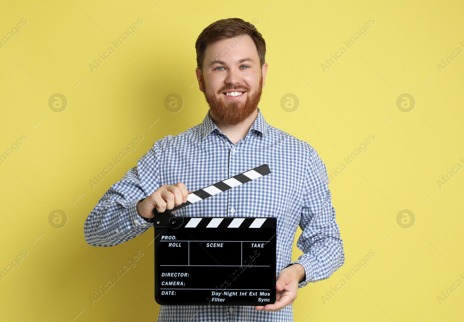 Photo of Making movie. Smiling man with clapperboard on yellow background