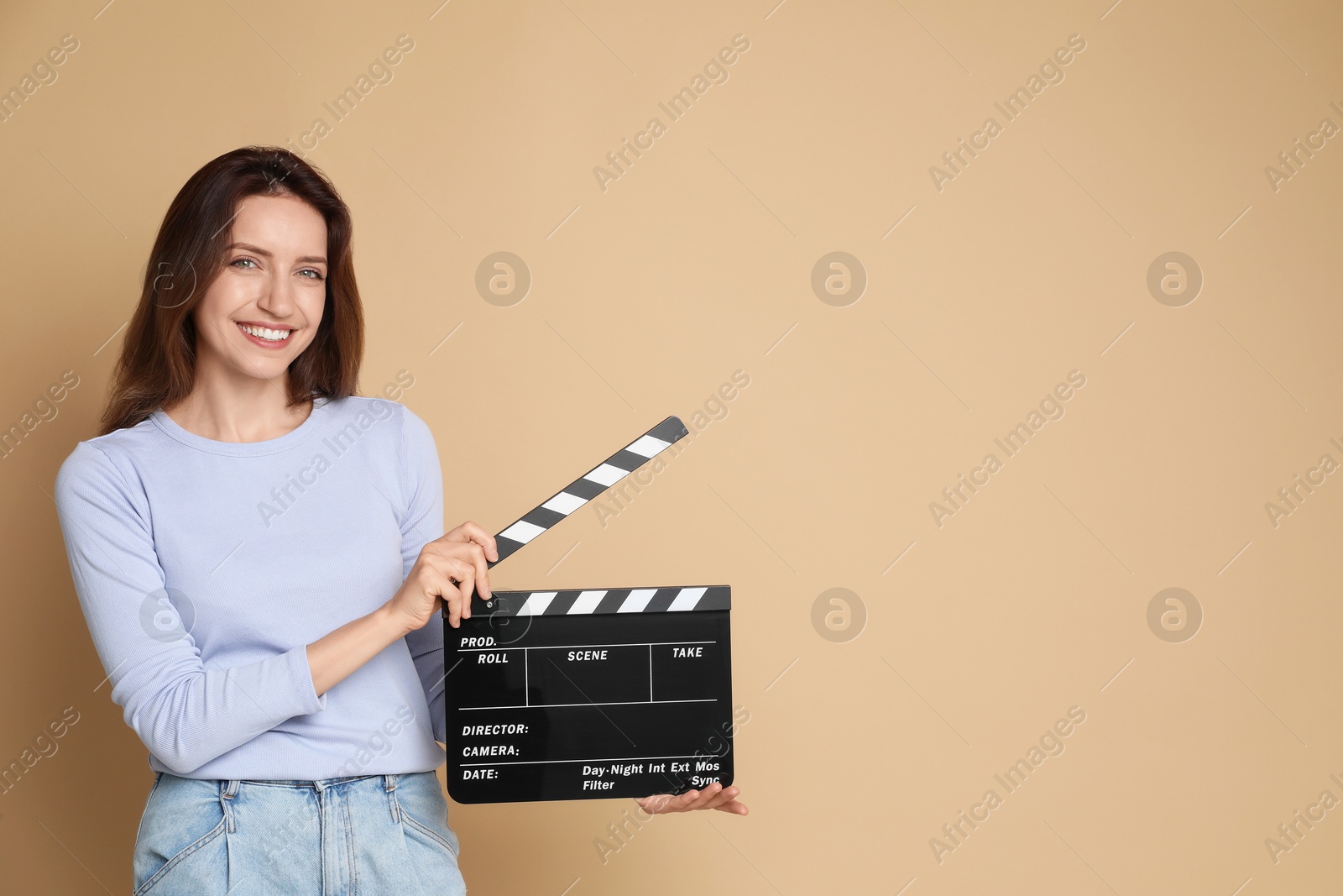 Photo of Making movie. Smiling woman with clapperboard on beige background. Space for text