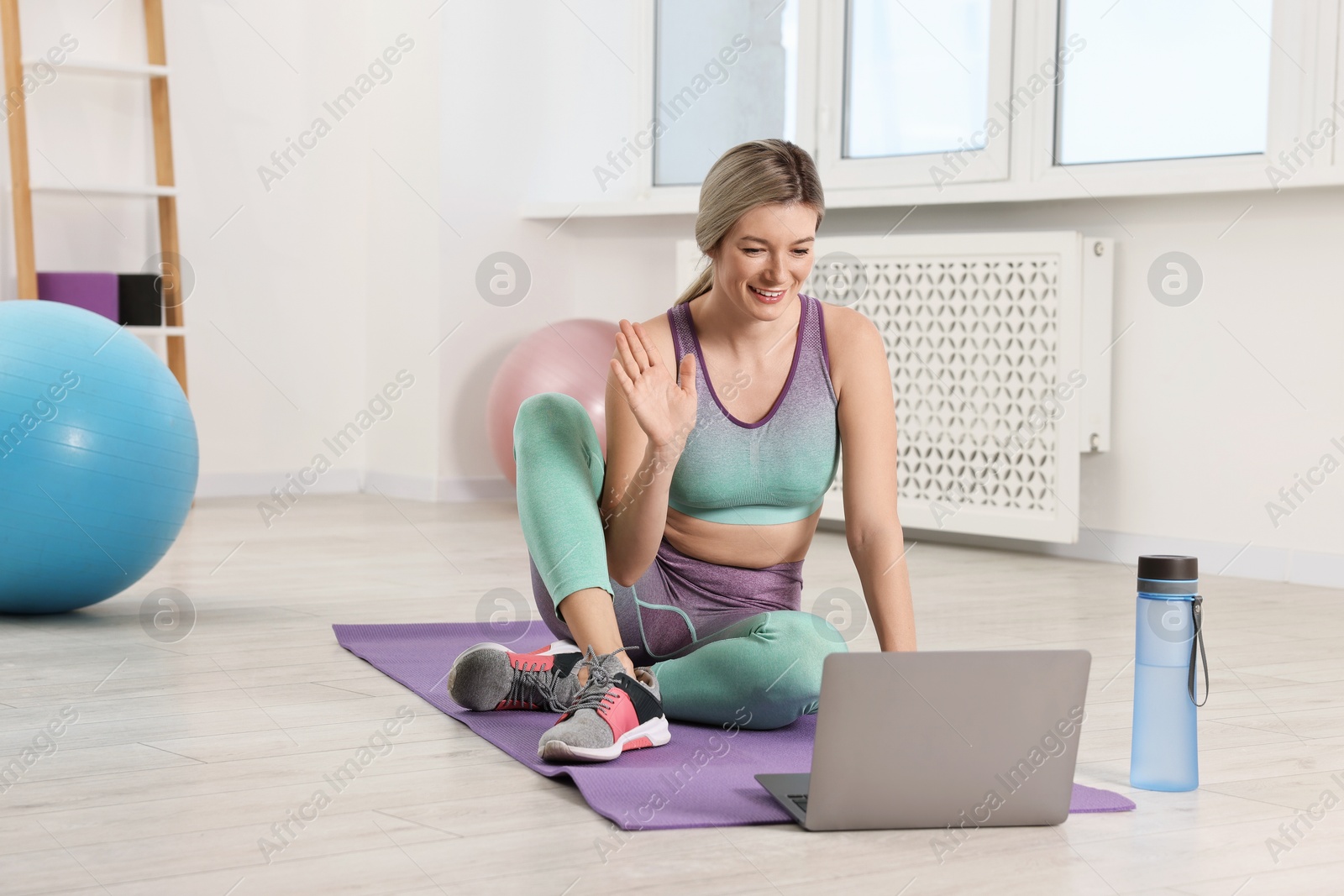 Photo of Online fitness trainer. Woman having video chat via laptop at home