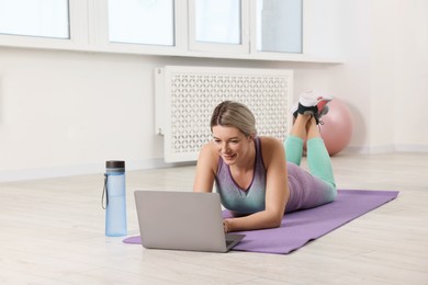 Photo of Online fitness trainer. Woman watching tutorial on laptop at home