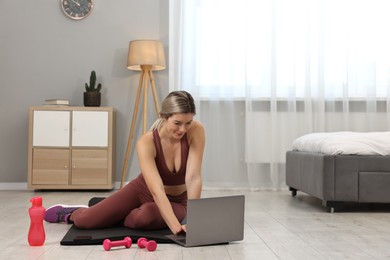 Photo of Online fitness trainer. Woman watching tutorial on laptop at home