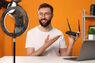 Photo of Smiling technology blogger recording video review about WI-FI router at home