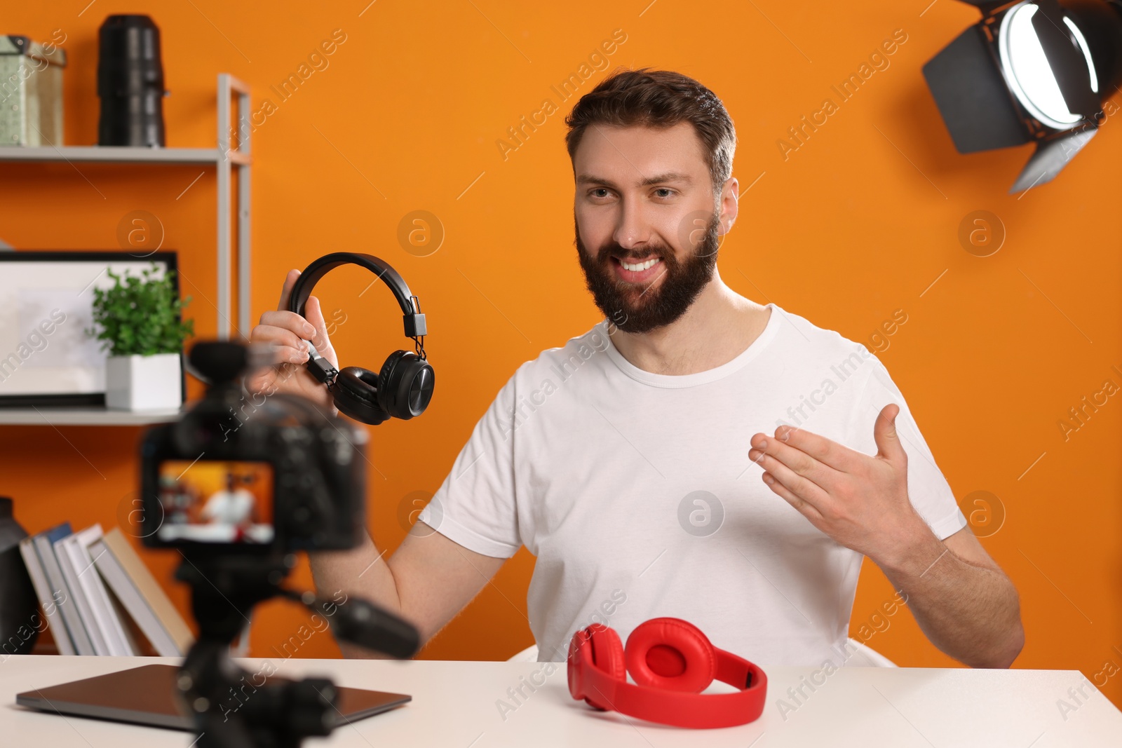 Photo of Smiling technology blogger recording video review about headphones at home