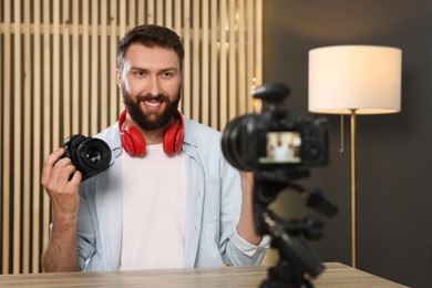 Smiling technology blogger with camera recording video review at home