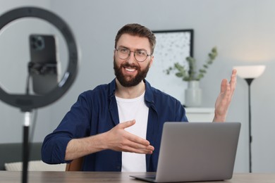 Smiling technology blogger with laptop recording video review at home