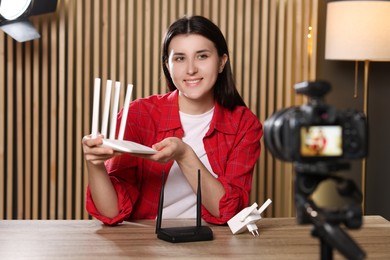 Smiling technology blogger recording video review about WI-FI devices at home