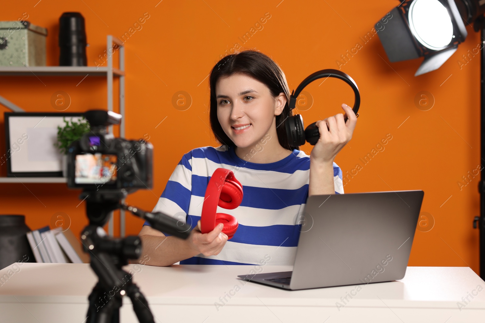 Photo of Smiling technology blogger recording video review about headphones at home