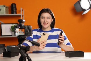 Smiling technology blogger recording video review about smartphones at home