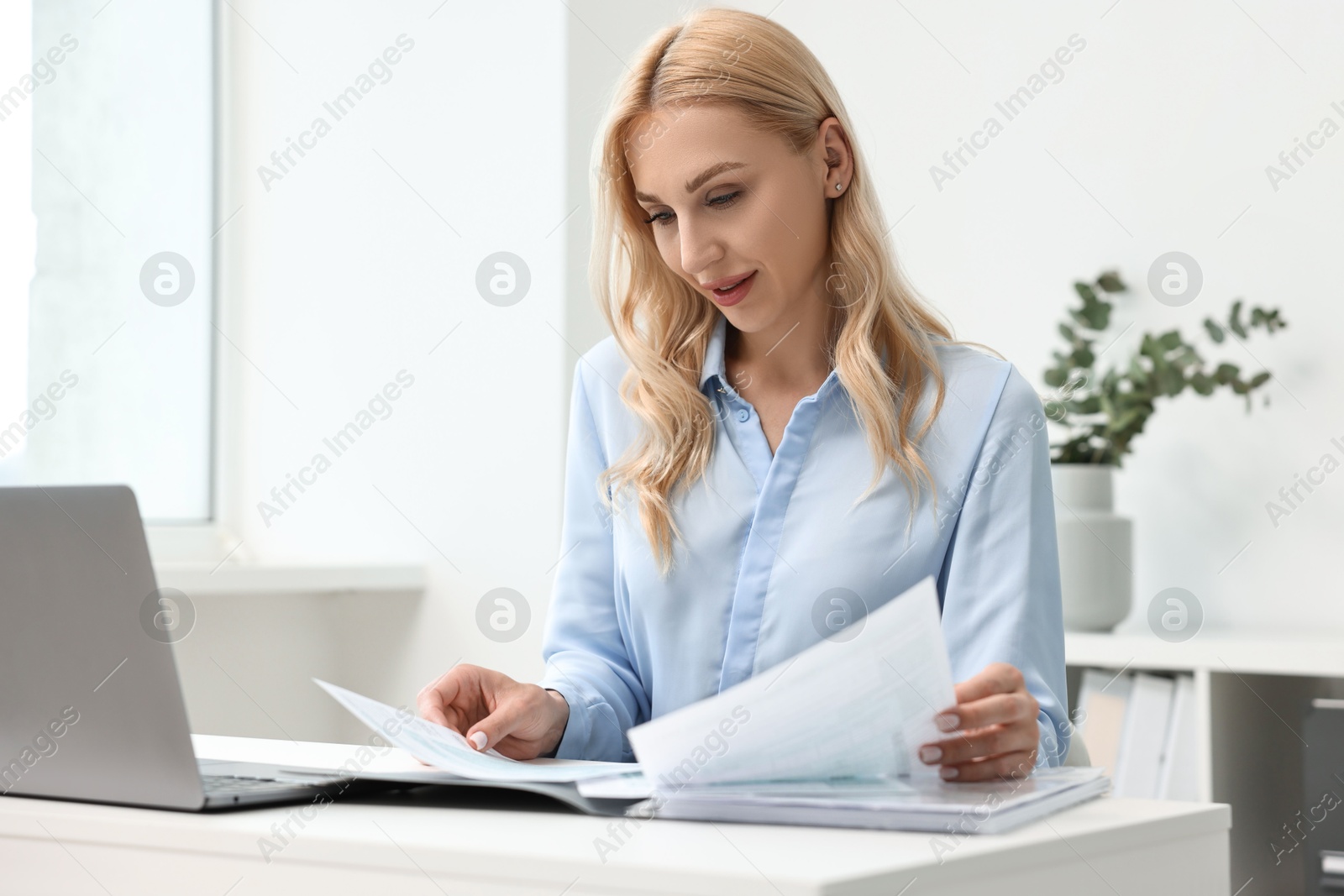 Photo of Happy secretary working with documents at table in office