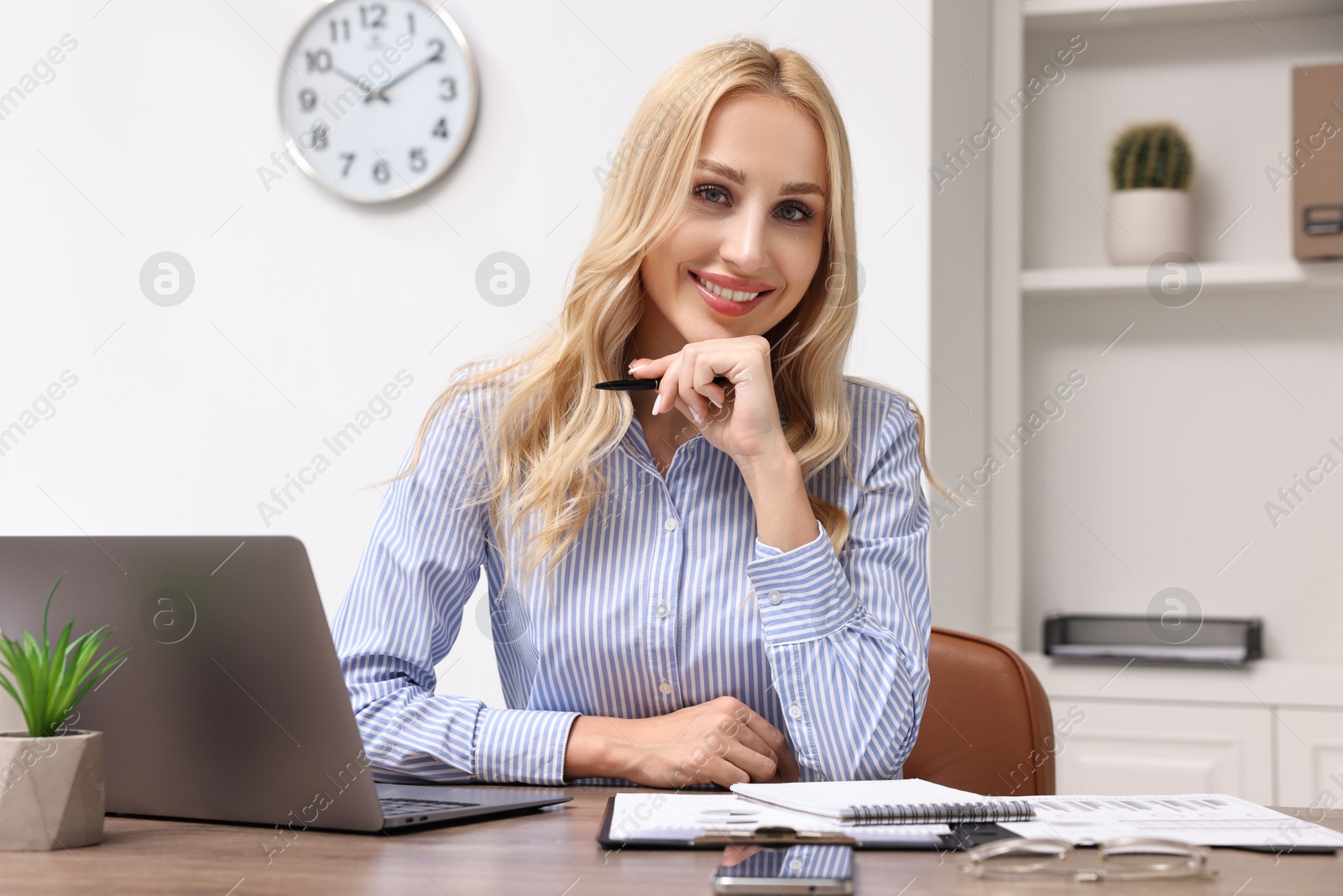 Photo of Happy secretary with pen at table in office