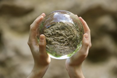 Photo of Stone surface outdoors, overturned reflection. Man holding crystal ball in forest, closeup