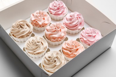 Photo of Tasty cupcakes in box on white background, closeup