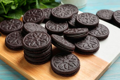 Photo of Board with tasty sandwich cookies on light blue wooden table, closeup