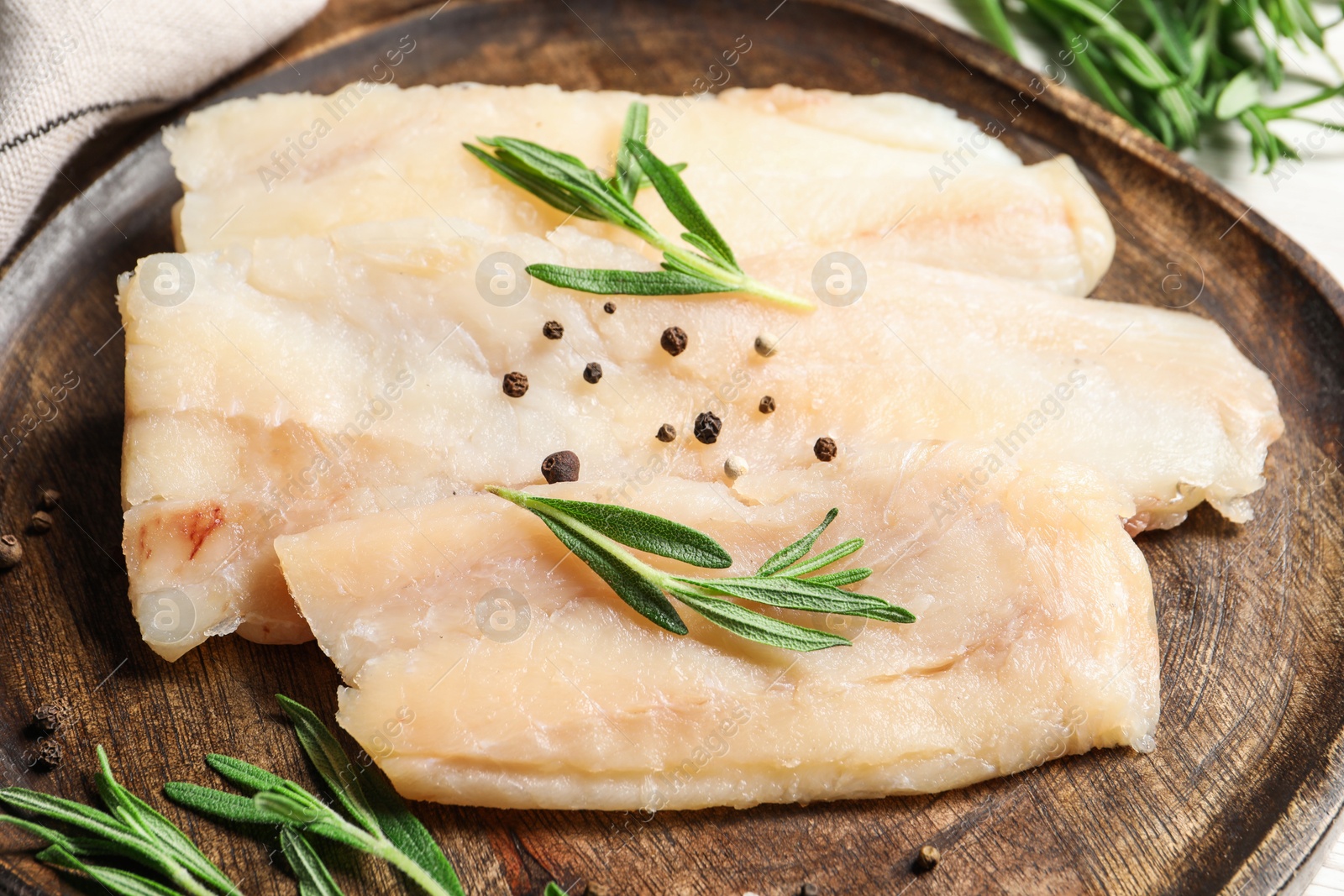 Photo of Raw cod fish, rosemary and spices on table, closeup