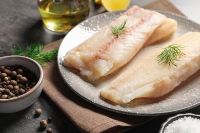 Photo of Pieces of raw cod fish, dill and peppercorns on table, closeup