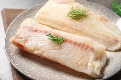 Photo of Pieces of raw cod fish and dill on table, closeup