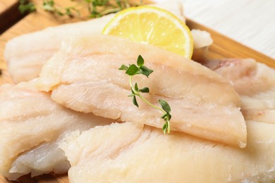 Photo of Pieces of raw cod fish and lemon on table, closeup