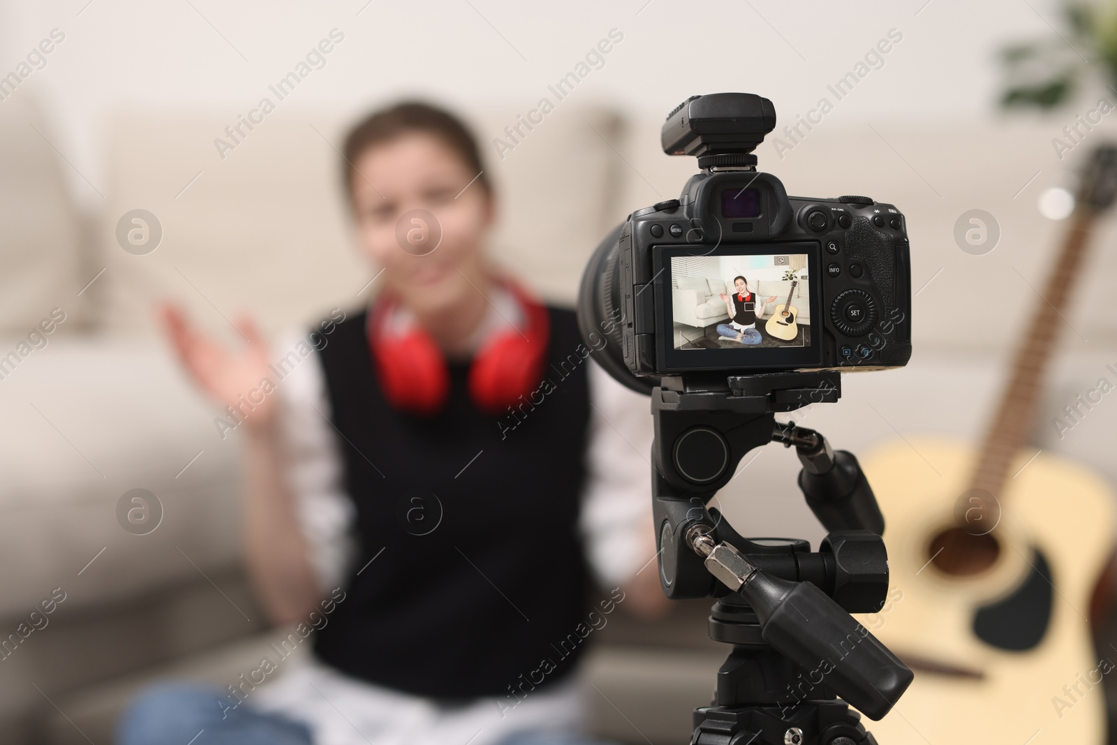 Photo of Teenage blogger explaining something while streaming at home, focus on camera