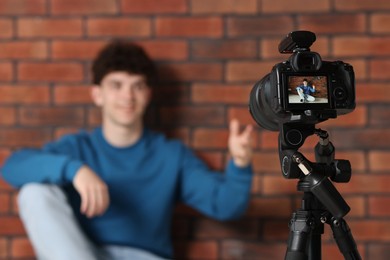 Teenage blogger explaining something while streaming indoors, focus on camera