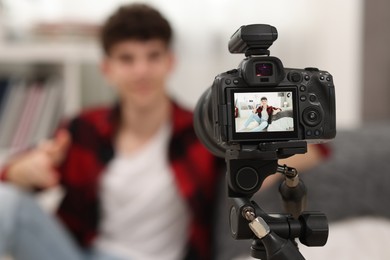 Photo of Teenage blogger explaining something while streaming at home, focus on camera