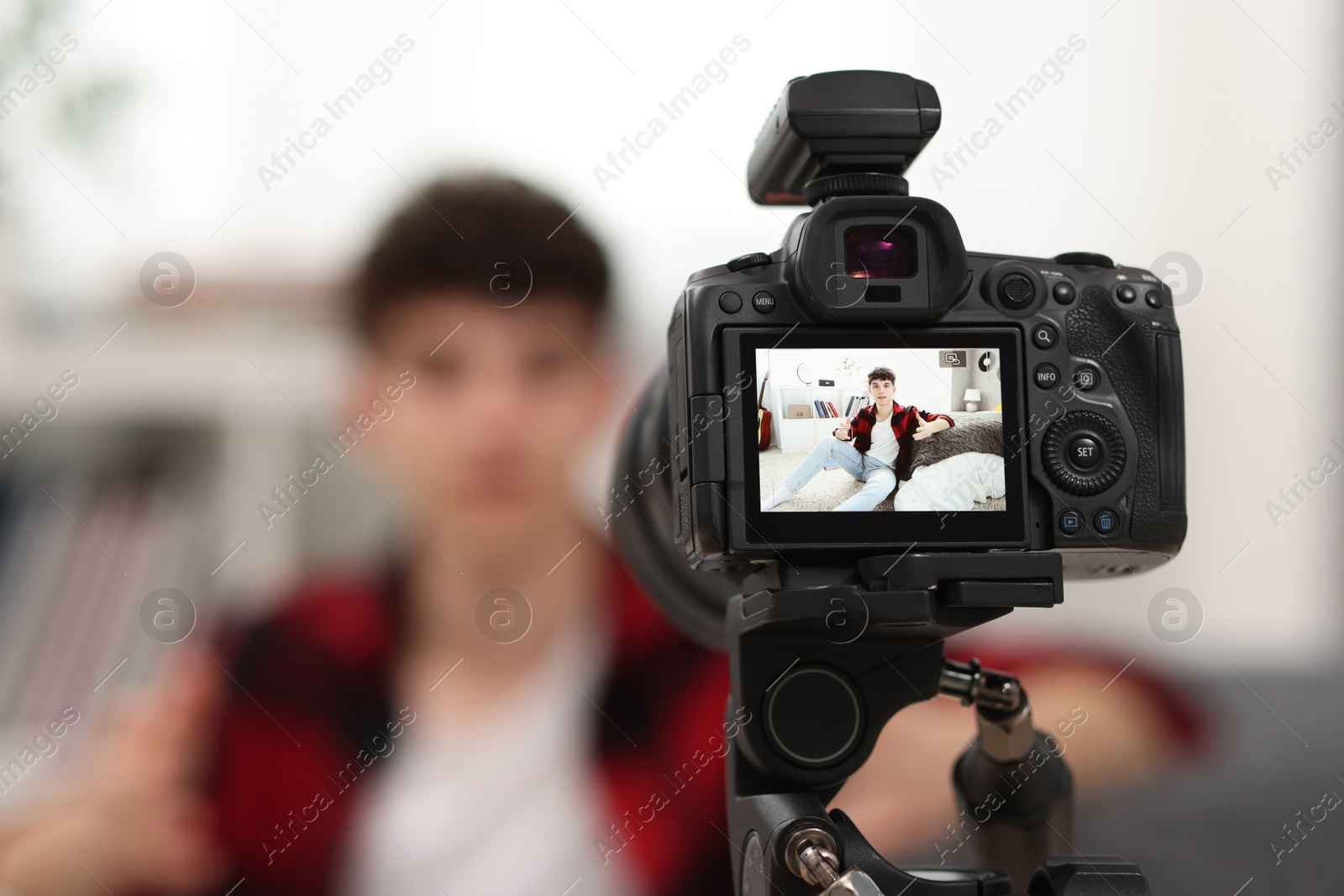 Photo of Teenage blogger explaining something while streaming at home, focus on camera