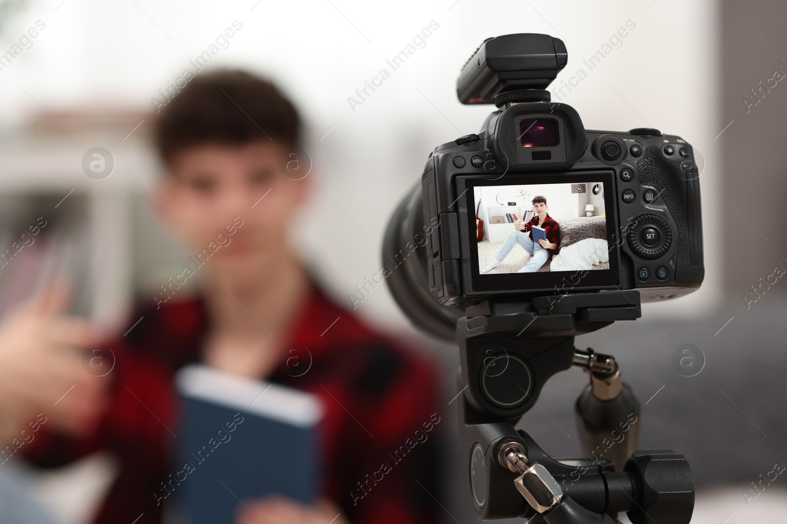 Photo of Teenage blogger explaining something while streaming at home, focus on camera