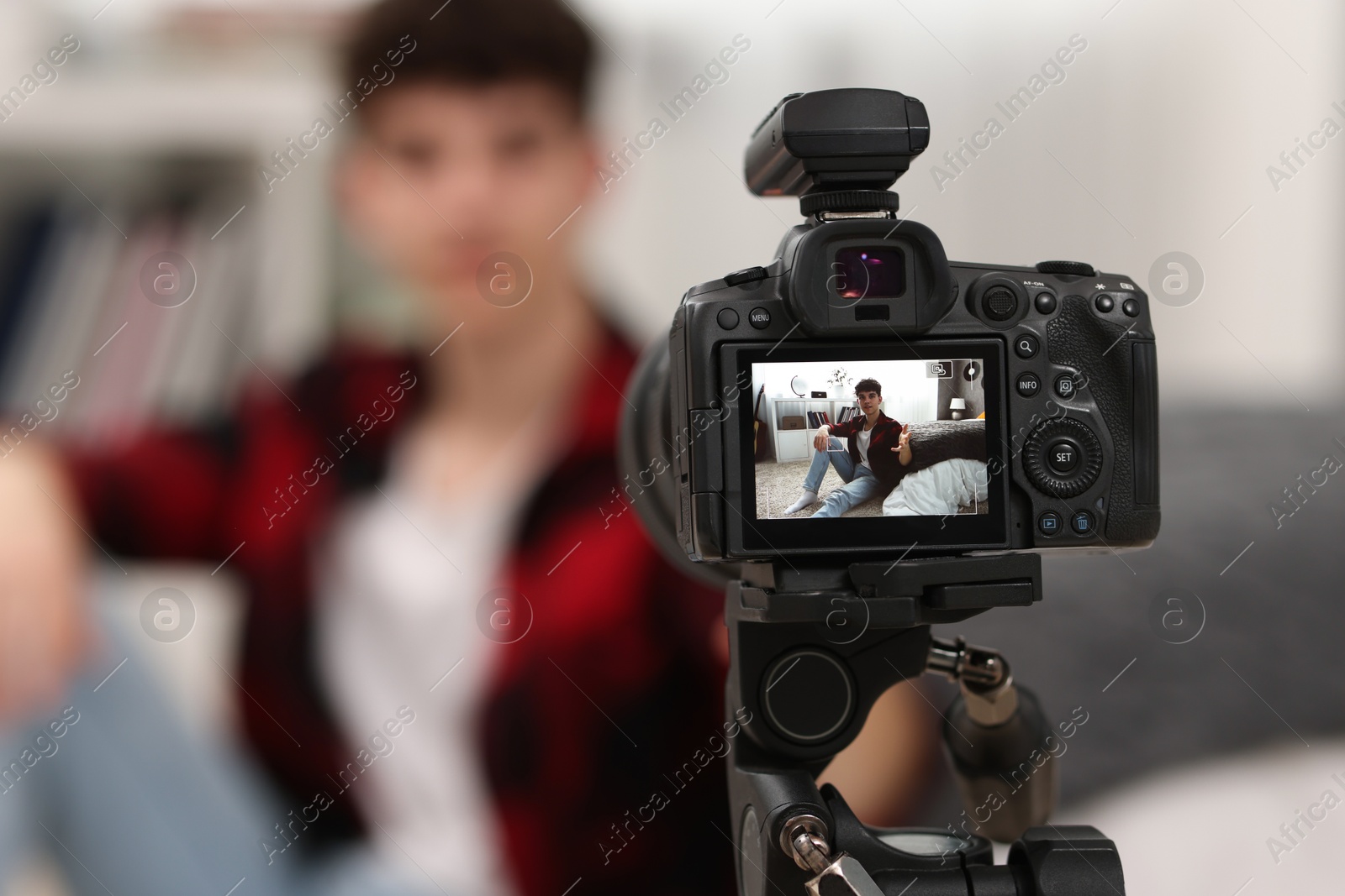 Photo of Teenage blogger explaining something while streaming at home, focus on camera