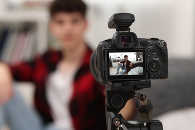 Photo of Teenage blogger explaining something while streaming at home, focus on camera