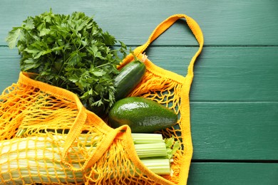 String bag with different vegetables on green wooden table, top view