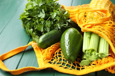 String bag with different vegetables on green wooden table, closeup