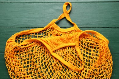 Photo of Orange string bag on green wooden table, top view