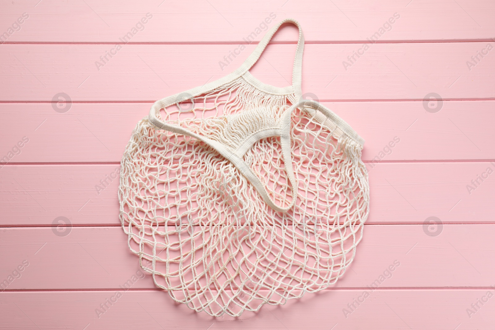 Photo of White string bag on pink wooden table, top view