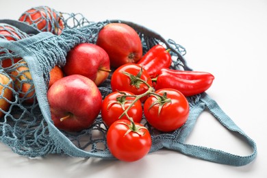 String bag with vegetables and apples on light grey background, closeup