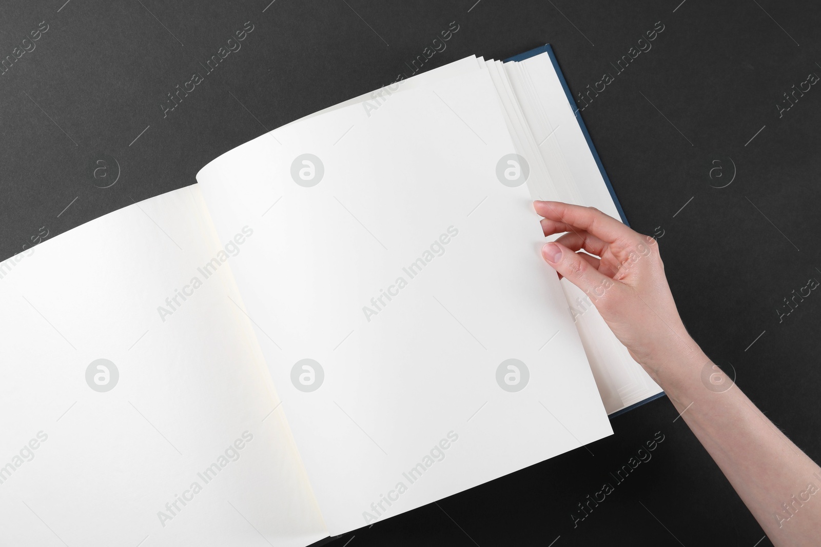 Photo of Woman with open photo album at black table, top view. Space for text