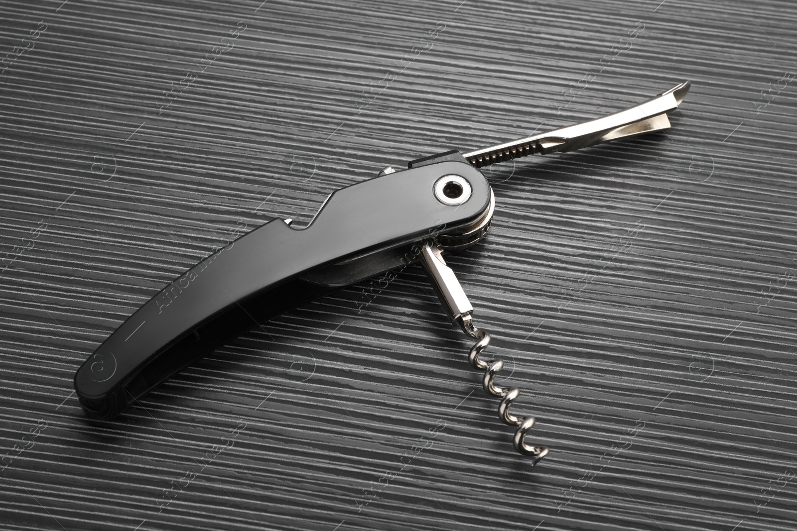 Photo of One corkscrew (sommelier knife) on black wooden table, top view