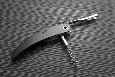 Photo of One corkscrew (sommelier knife) on black wooden table, top view