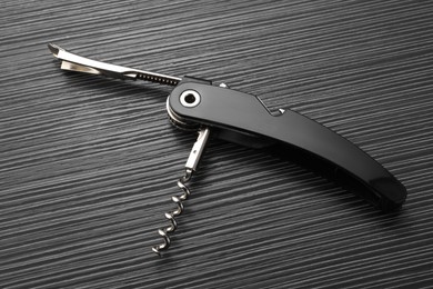 Photo of One corkscrew (sommelier knife) on black wooden table, top view