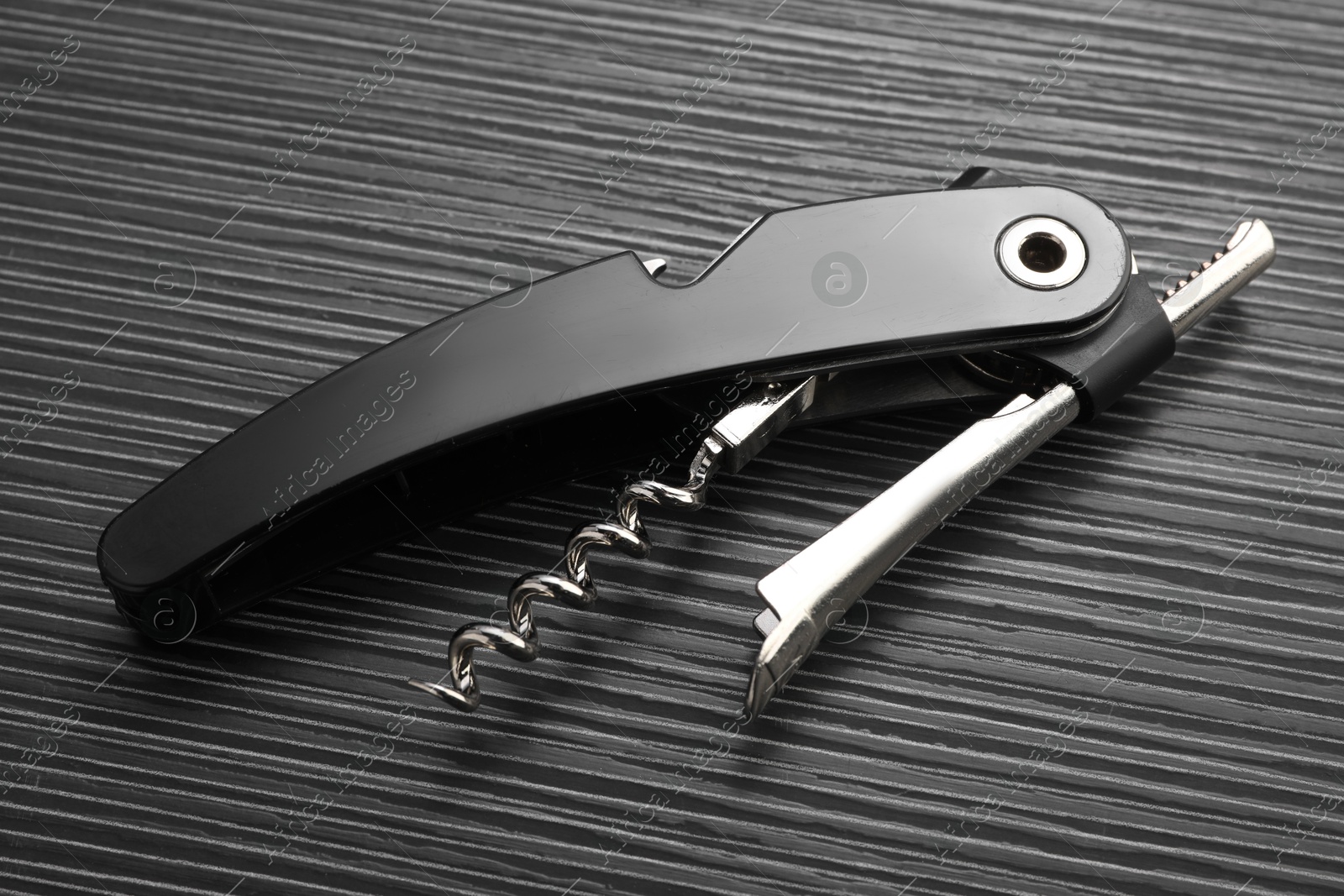 Photo of One corkscrew (sommelier knife) on black wooden table