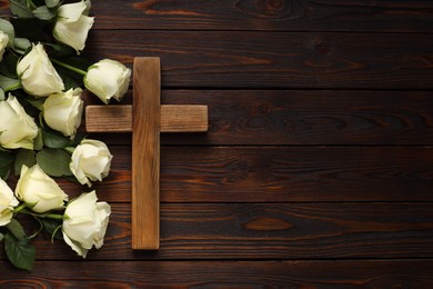 Photo of Cross and roses on wooden table, top view with space for text. Religion of Christianity