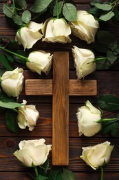 Photo of Cross and roses on wooden table, top view. Religion of Christianity