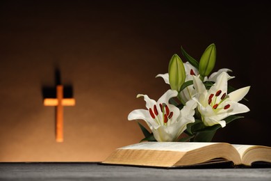 Bible and lilies on gray table in church. Religion of Christianity