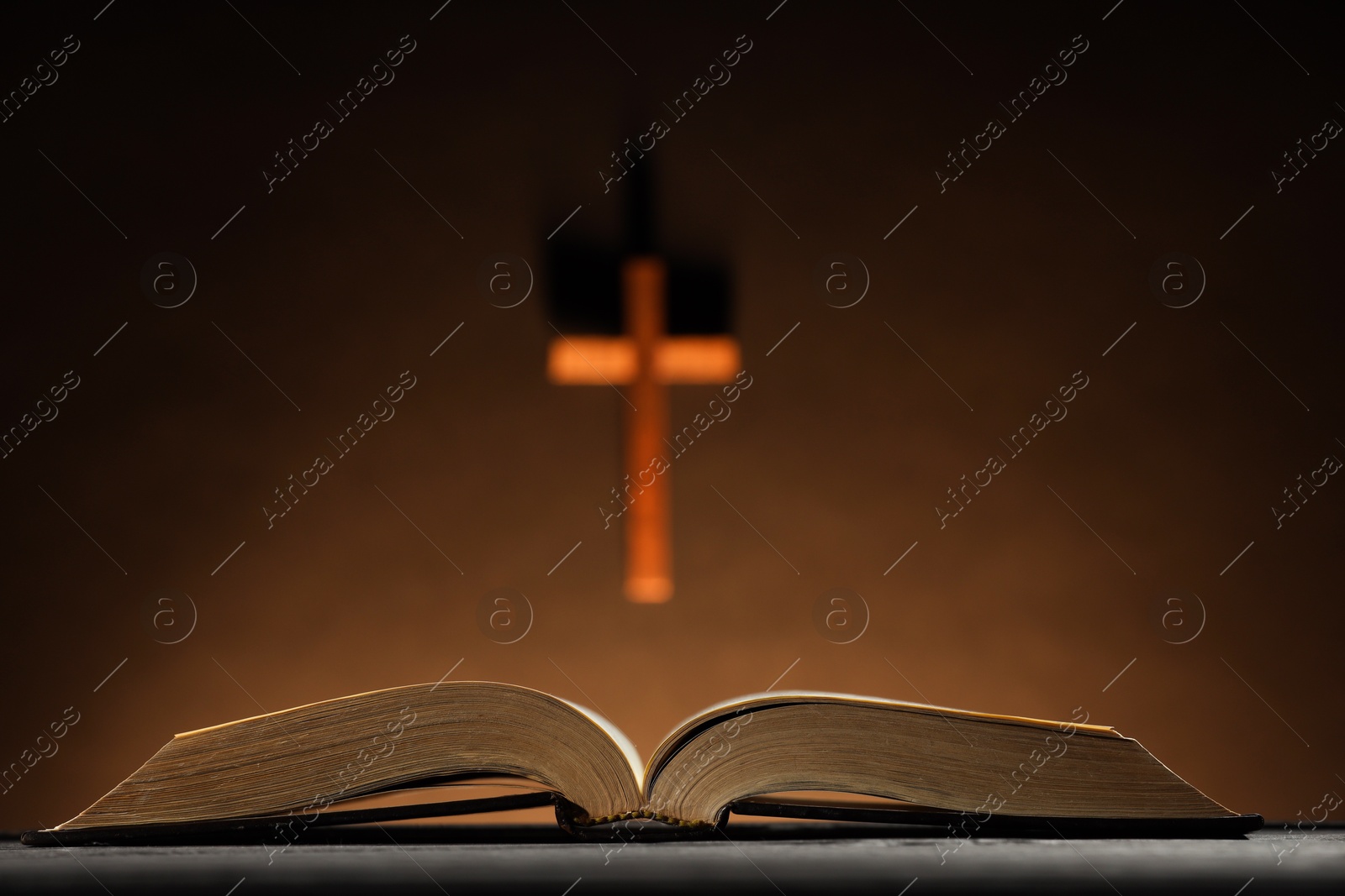 Photo of Bible and cross on brown wall, selective focus. Religion of Christianity